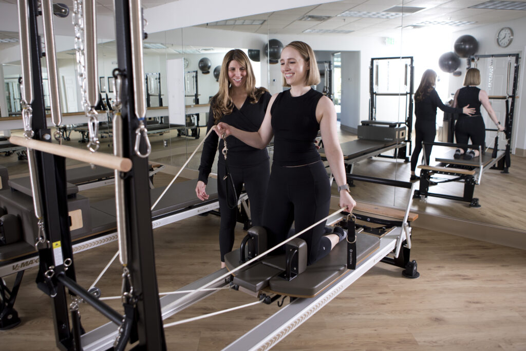 Photos of Studio100 Pilates. Owner Shelly Burns assists client with Merrithew equipment and pilates practice.